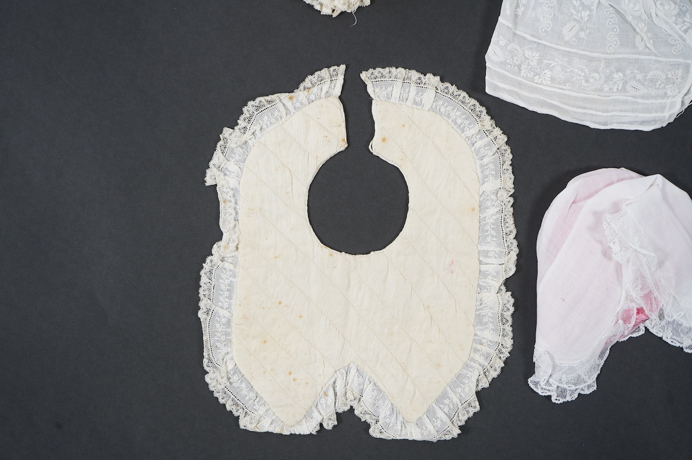 An 18th century Holly Point needle lace panelled linen baby bonnet, an early 19th century white worked baby bib and bonnet and a later 19th century finely ruffed lace bonnet (4). Condition - Holly Point bonnet and bib ha